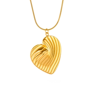 Macro shot of gold-plated heart pendant with rippled texture and sleek snake chain