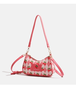 Détail macro du motif cerise rose sur un sac à bandoulière en similicuir matelassé