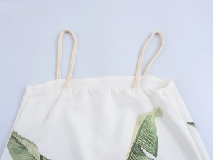 Detailed view of woven rope shoulder straps and green palm leaf print on white fabric