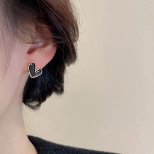 Close-up of elegant black heart stud earrings with golden edges on model's ear