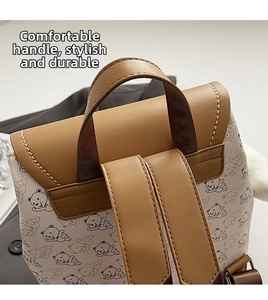 Gros plan sur la poignée en cuir marron et les coutures renforcées du sac à dos fleuri