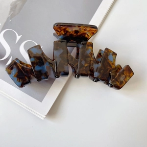 Detailed macro view of large acetate hair claw with tortoiseshell pattern and blue accents