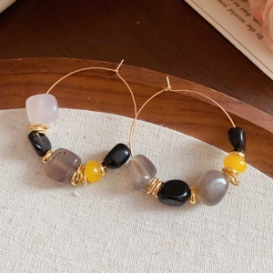 Close-up of bohemian gold hoop earrings with colorful agate beads on rustic wood