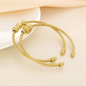 Detailed macro view of gold-plated twisted cable bracelets with polished bead accents