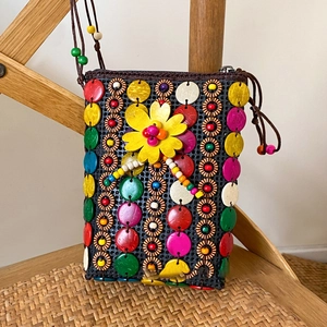 Detail of bohemian handmade woven bag with colorful wooden buttons and yellow flower accent