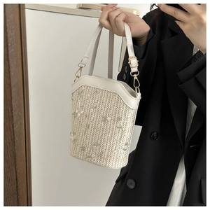 Détail du sac seau en paille tissée avec broderie florale et garniture en similicuir