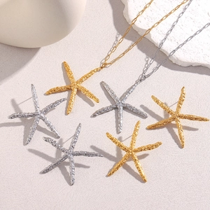 Macro detail of 18K gold starfish earrings and necklace set with hammered texture