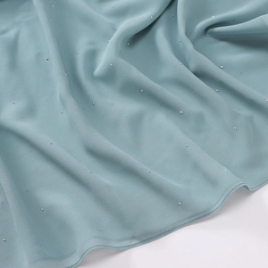 Detailed view of light teal chiffon fabric with shimmering silver glitter and soft pleats