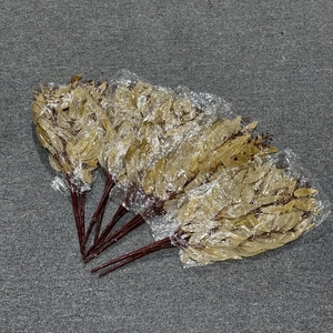 Five bundles of artificial beige willow leaves in clear plastic packaging on a grey carpet