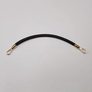 Detail of a black leather handbag strap with elegant gold metal buckles and clips