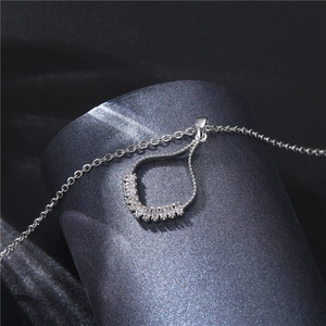 Silver skirt-shaped necklace with zircon pavé fan pendant on a dark elegant background