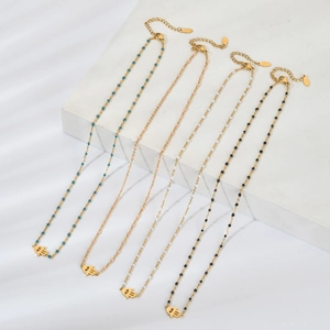 Détail de quatre colliers Main de Fatma dorés avec perles colorées sur pierres blanches