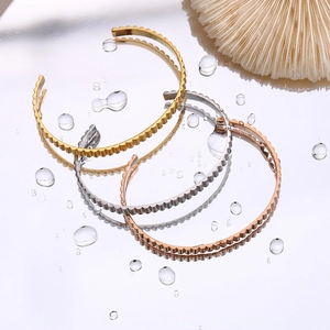 Detail of open bangles in gold, silver, and rose gold with scallop wave edges