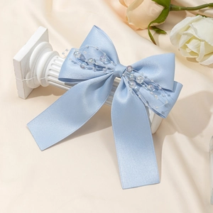 Elegant blue satin bow hair clip with pearls and glass beads on a Roman pillar