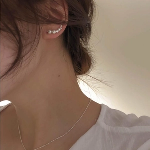 Detail view of a model wearing S925 silver minimalist beaded pearl earrings and a fine chain
