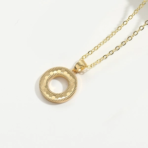 Macro view of gold round necklace pendant featuring detailed scale texture and fine chain