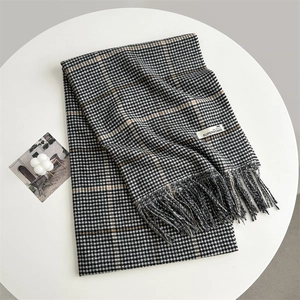Close-up of black, white and brown houndstooth scarf with fringe and a woven brand label