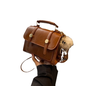 Retro brown PU leather crossbody bag with top handle and gold hardware on white background