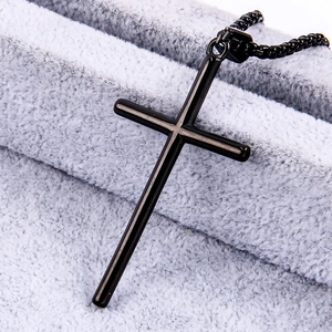 Close-up of black polished stainless steel cross pendant on soft plush background