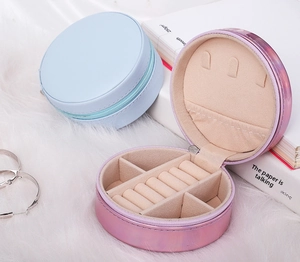 Macro view of open pink round PU leather jewelry box showing ring slots and earring board
