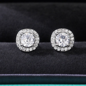 Macro view of round and square zircon stud earrings displayed in a black velvet box