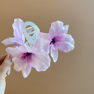 Detail of lycoris acrylic hair clip with pink gradient fabric flowers on white base
