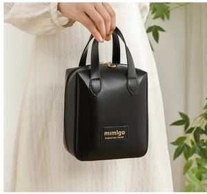 Detail of black PU leather toiletry bag featuring gold zipper and elegant top handle