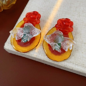 Macro detail of goldfish and flower earrings with amber resin base in high clarity