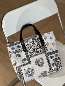 Detail of paisley pattern cotton linen tote with black leather handle and metal rivets