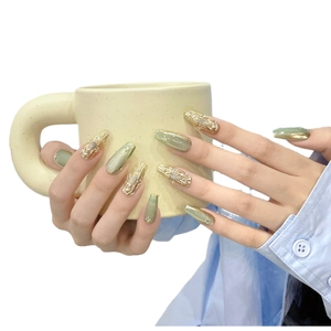 Green cat eye press-on nails with champagne gold accents and rhinestone decorations