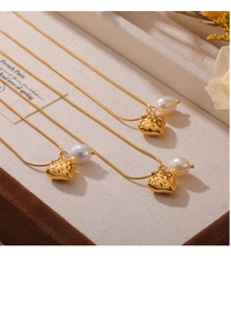 Gros plan détaillé du collier pendentif cœur doré avec perle d'eau douce et texture