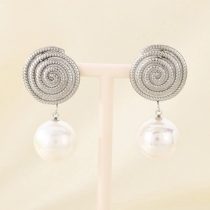 Detail of silver spiral textured earrings with large white hanging pearls on a display