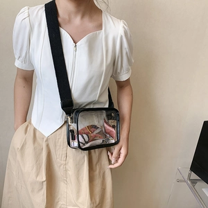 Close-up of clear PVC crossbody bag with a black woven strap and colorful silk scarf detail