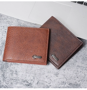 Close-up of brown leather wallets stacked on a marble surface near a laptop