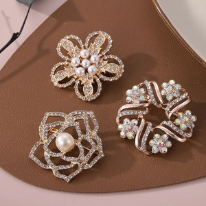 Broches fleurs dorées élégantes avec perles et cristaux sur une surface en cuir