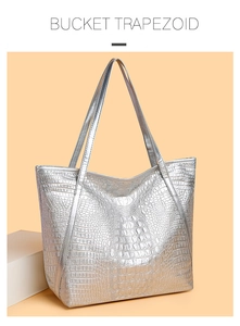 Detail of silver crocodile-patterned tote bag with polished finish and trapezoid shape