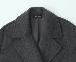Détail du col d'un manteau en laine gris foncé avec étiquette de marque NNWM WOMAN