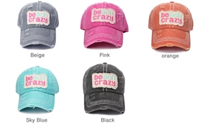 Flat lay of five distressed baseball caps in beige, pink, orange, blue, and black colors