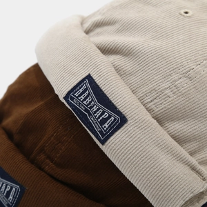 Macro detail of corduroy docker cap showing texture and woven label in beige and brown