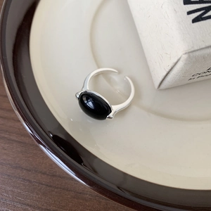 Macro shot of oval black onyx gemstone set on vintage adjustable silver ring band