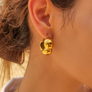 Detailed close-up of 18k gold-plated triple sphere earrings worn by a model