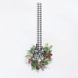 Detailed view of mini Christmas wreath with snowy pine needles, red berries and checkered ribbon