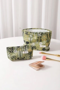 Detail showing embroidered olive green cotton linen makeup bags with floral patterns