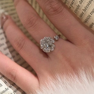 Close-up of a silver zircon camellia flower open ring worn on a finger