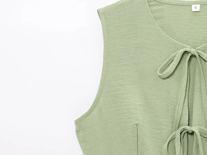 Detailed view of grass green knitted tank top featuring tie-neck and ribbed fabric texture