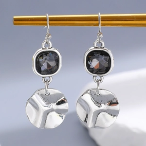 Detail of silver drop earrings with square black crystal and hammered metal discs
