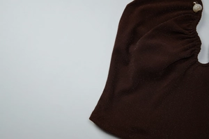 Close-up of brown knit fabric with pearl accents and subtle gold shimmer details