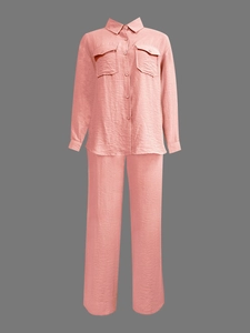 Detail of coral pink pleated fabric set featuring long-sleeve shirt and wide-leg trousers