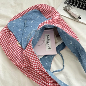 Detail of red gingham tote bag featuring blue denim lining and delicate bow embroidery