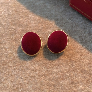 Retro deep red flocked oval earrings with gold metal frame on a warm beige background